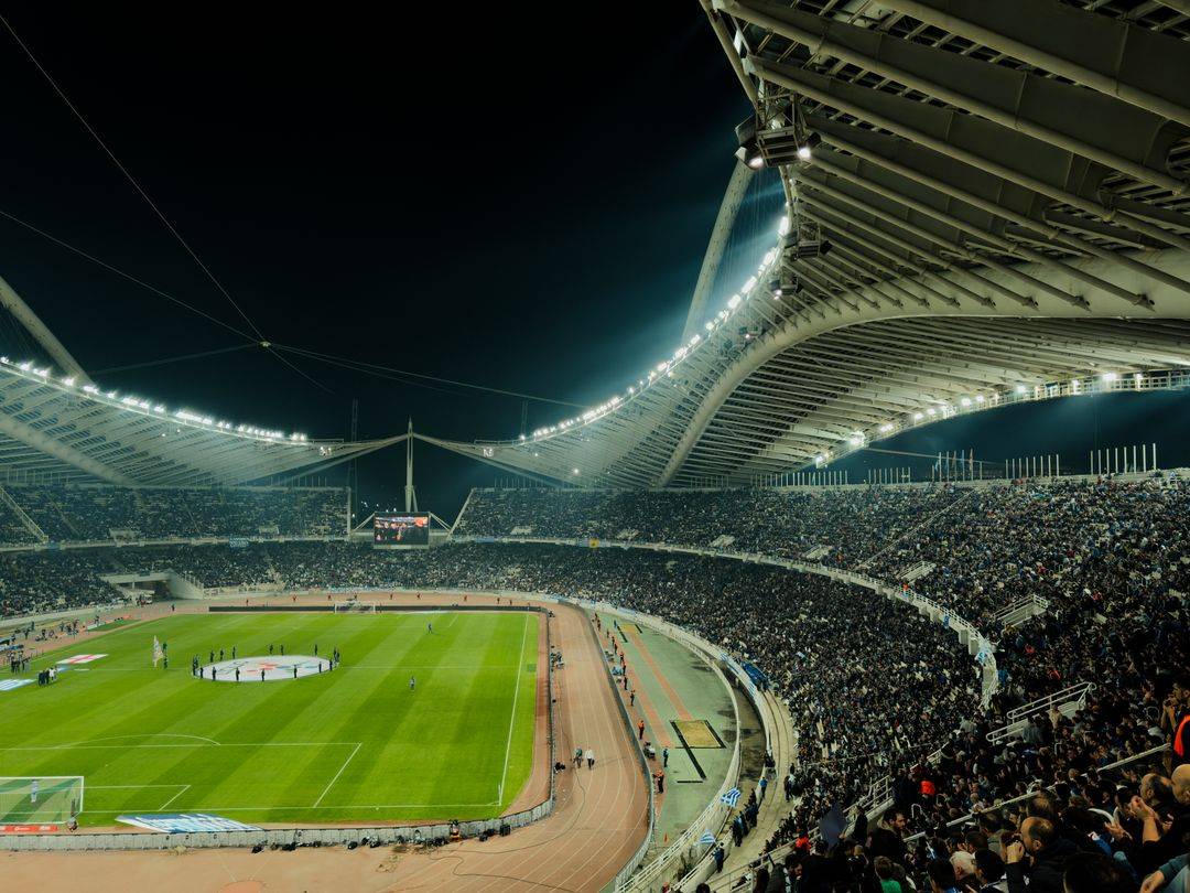 Stadion sepak bola menyala di malam hari dengan penonton memadati tribun
